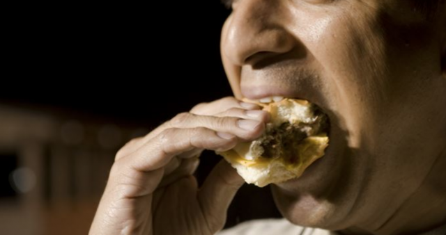 Hombre comiendo una hamburguesa