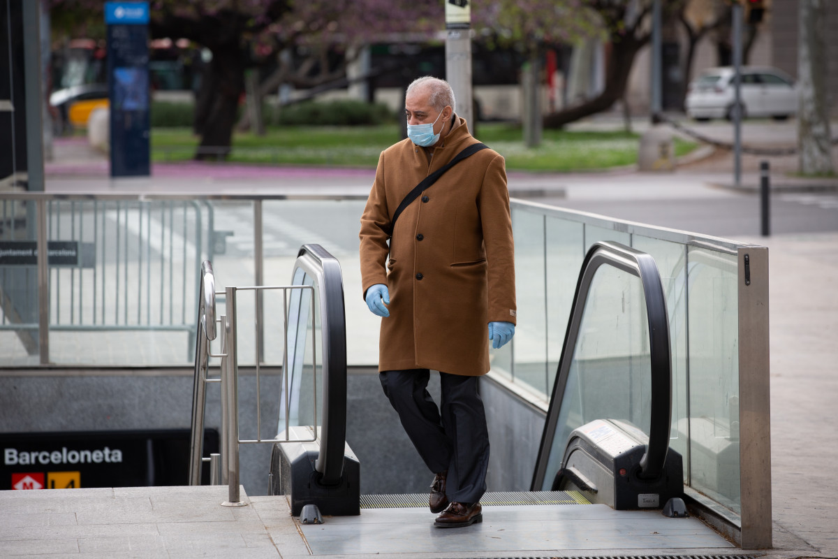 Un home protegit amb una mascarilla i guants de làtex surt del metre durant el segon dia laborable de l'estat d'alarma pel coronavirus, a Barcelona/Catalunya (Espanya), a 17 de març de 2020.