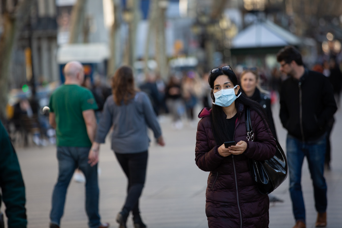 Una mujer con mascarilla camina por las Ramblas de Barcelona.