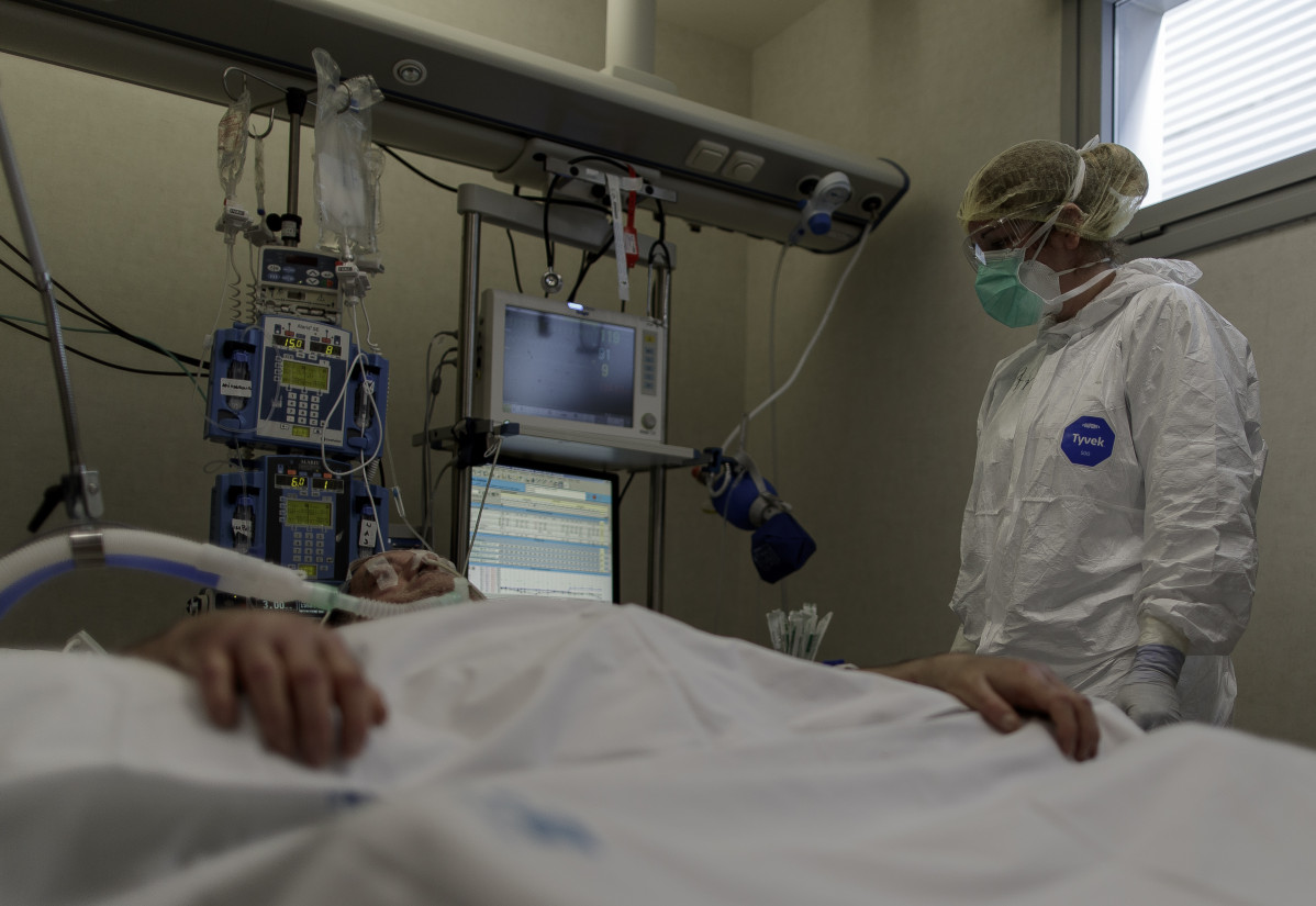 Personal sanitario totalmente protegido atiende a un paciente ingresado en la Unidad de Cuidados Intensivos del Hospital Infanta Sofía en San Sebastián de los Reyes (Madrid).