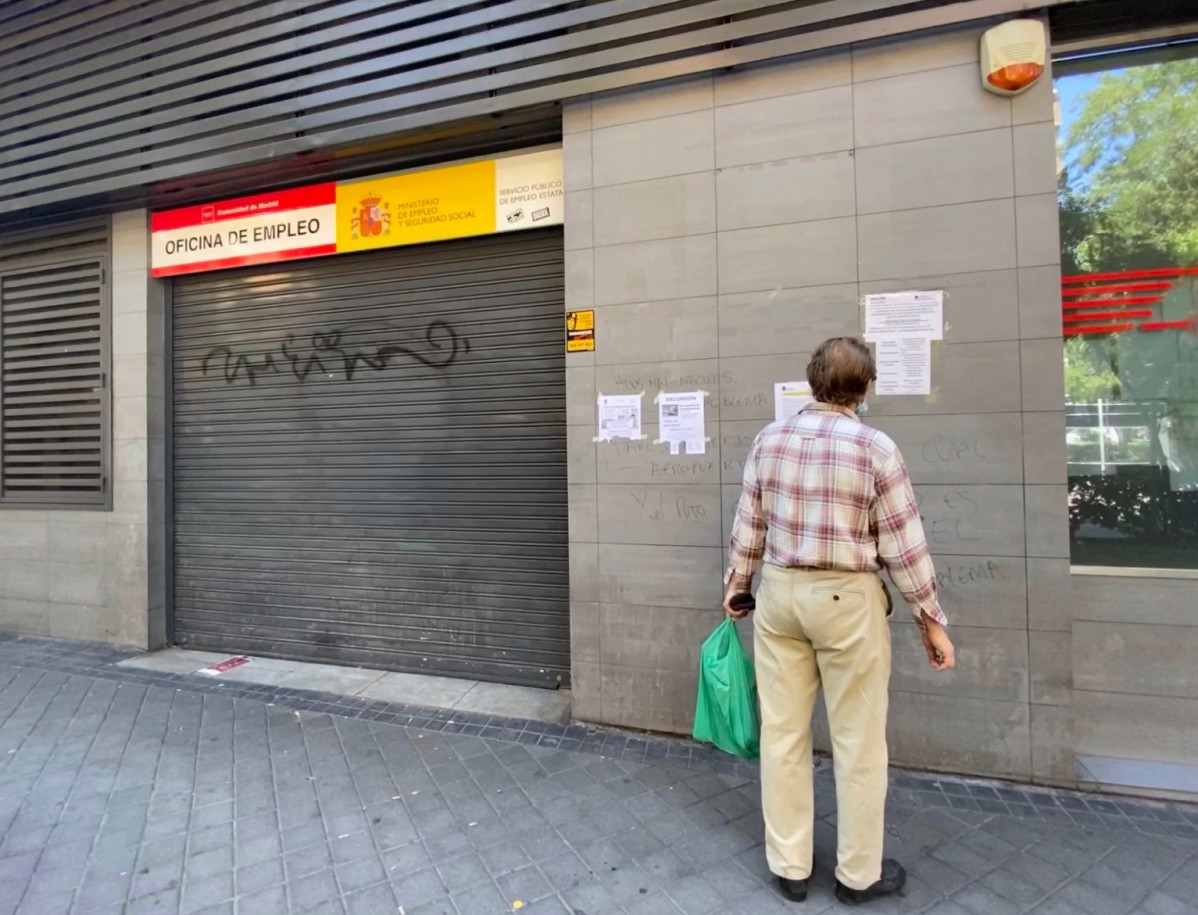 Una persona observa uno de los carteles con instrucciones para hacer trámites por internet colocados en la fachada de una oficina del SEPE