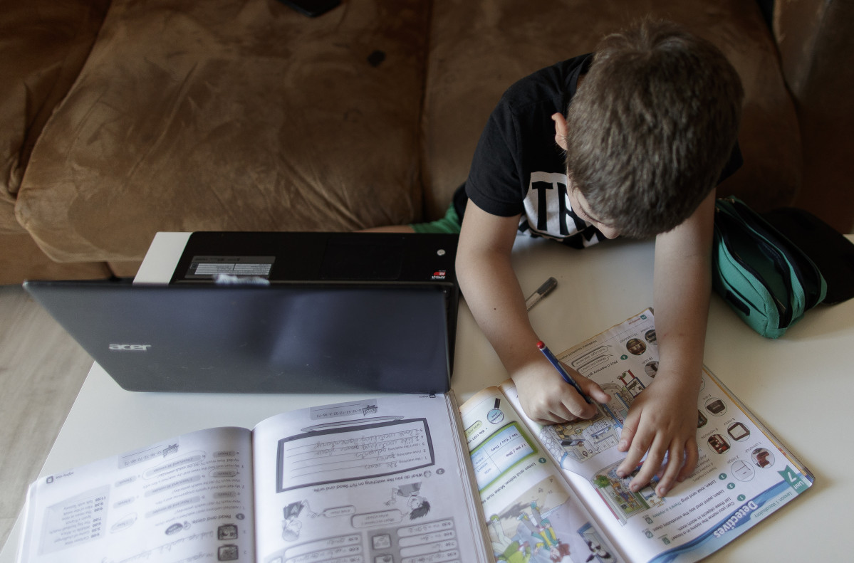 Un alumno de primaria hace los deberes de la asignatura de Inglés con varios libros y un ordenador a menos de un mes de terminar en casa el curso escolar 2019-2020 por la pandemia del Covid-19, en Ma