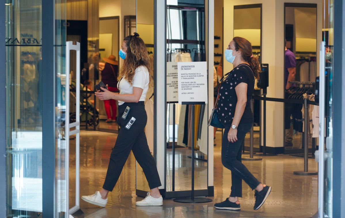 Compradores con mascarillas en el interior de una tienda de moda en el inicio de la Fase 2 en Sevilla a 25 de mayo 2020