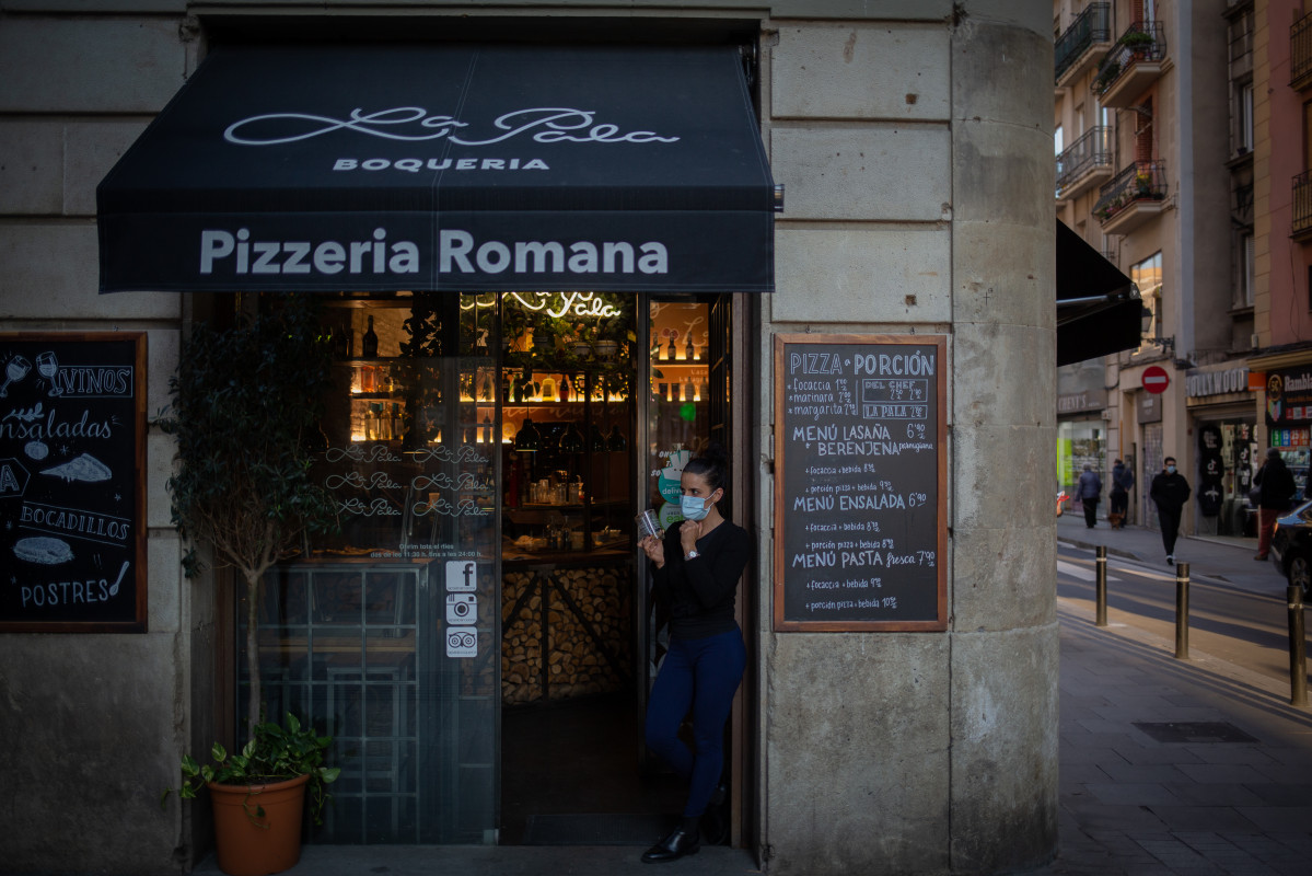 Una trabajadora observa las inmediaciones de su establecimiento de Barcelona, Catalunya (España), tras la paralización de la actividad durante dos semanas en bares restaurantes, el 16 de octubre del