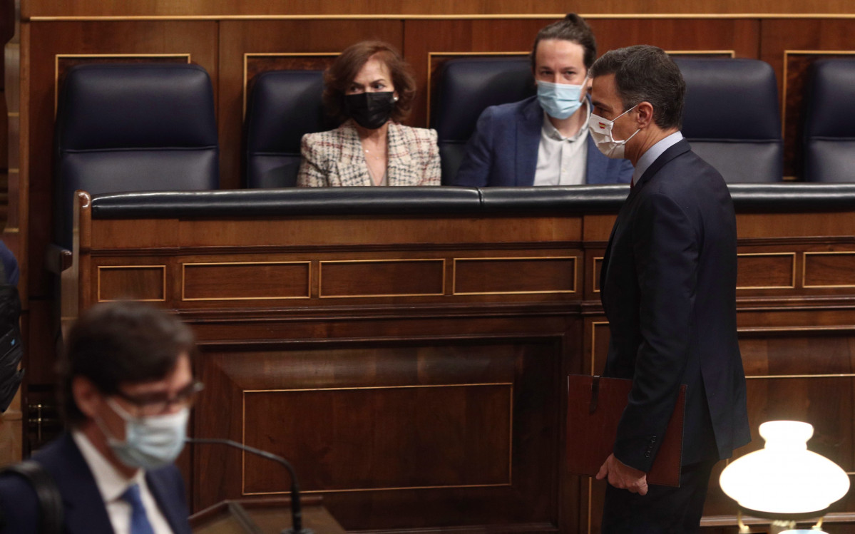 El presidente del Gobierno, Pedro Sánchez, pasa por delante la vicepresidenta primera del Gobierno, Carmen Calvo, y el vicepresidente segundo del Gobierno, Pablo Iglesias, durante una sesión de cont