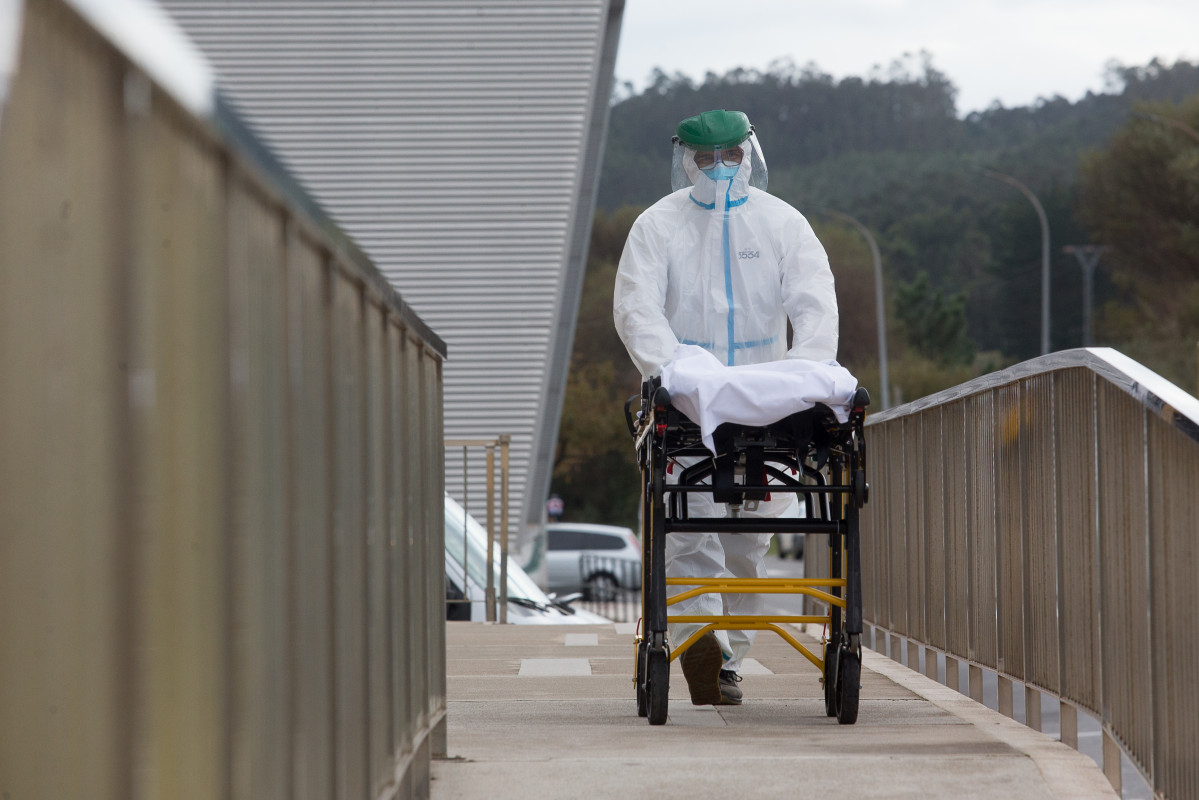 Un trabajador sanitario totalmente protegido traslada una camilla en las inmediaciones de la residencia de ancianos de San Cibrao donde se ha originado un brote de Covid-19, en San Cibrao, Lugo, Galic