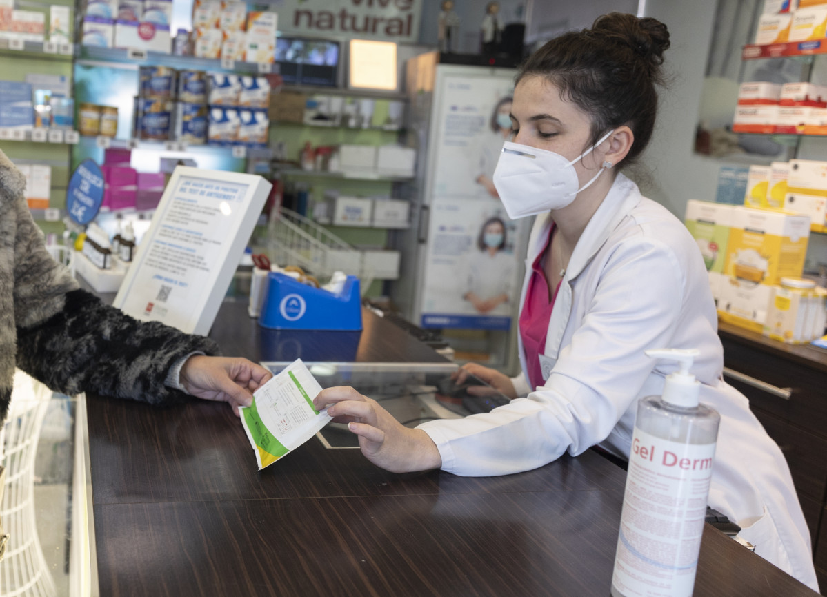 Una farmacéutica muestra un test de antígenos a una persona en la farmacia ‘Las Gemelas’, a 10 de enero de 2022, en Madrid (España). El presidente del Gobierno, ha anunciado que el Gobierno tie