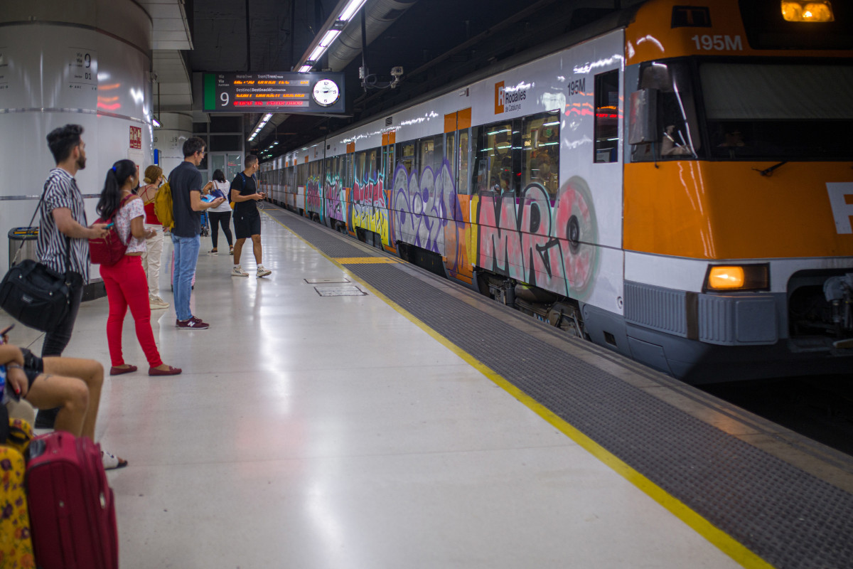 Archivo - Viajeros esperan la llegada de un tren en uno de los andenes de la estación de Sants.