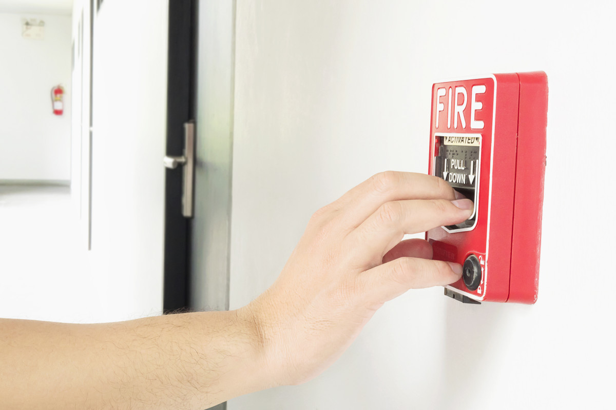 Hombre llegando su mano empujar estacion mano alarma incendio