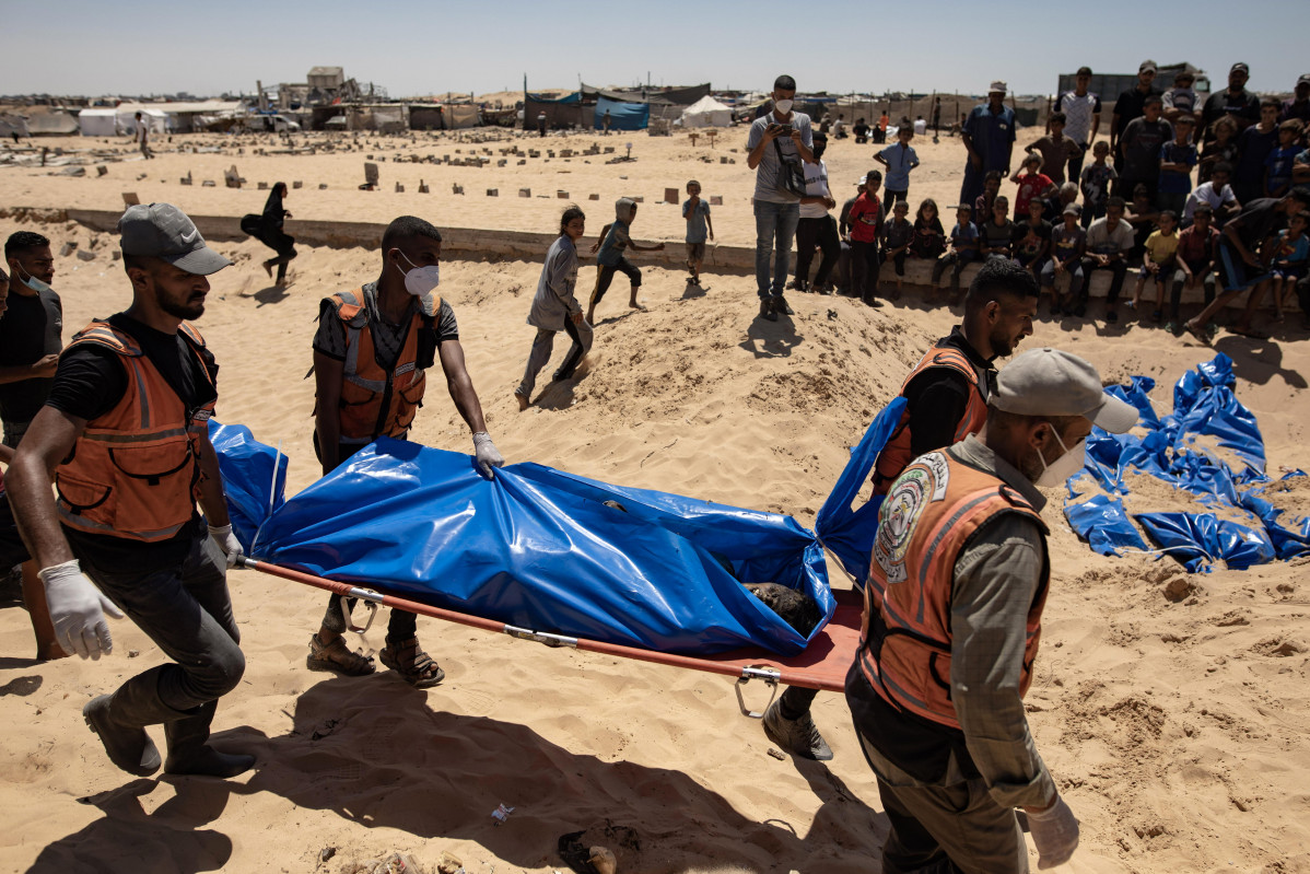 Gaza (-), 05/08/2024.- People watch as health workers prepare to bury the bodies of 84 Palestinian handed over by Israeli forces, in Khan Younis, southern Gaza Strip, 05 August 2024. The bodies were b