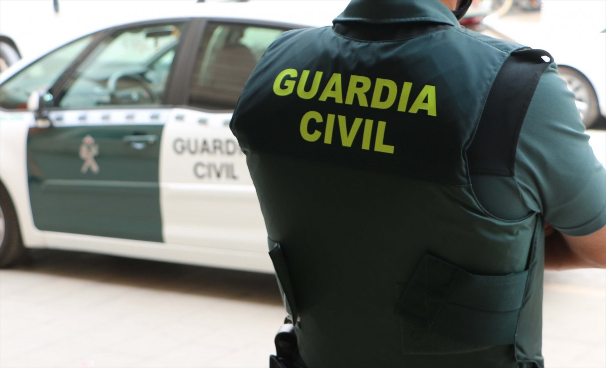 EuropaPress 4256421 agente guardia civil espaldas junto vehiculo oficial