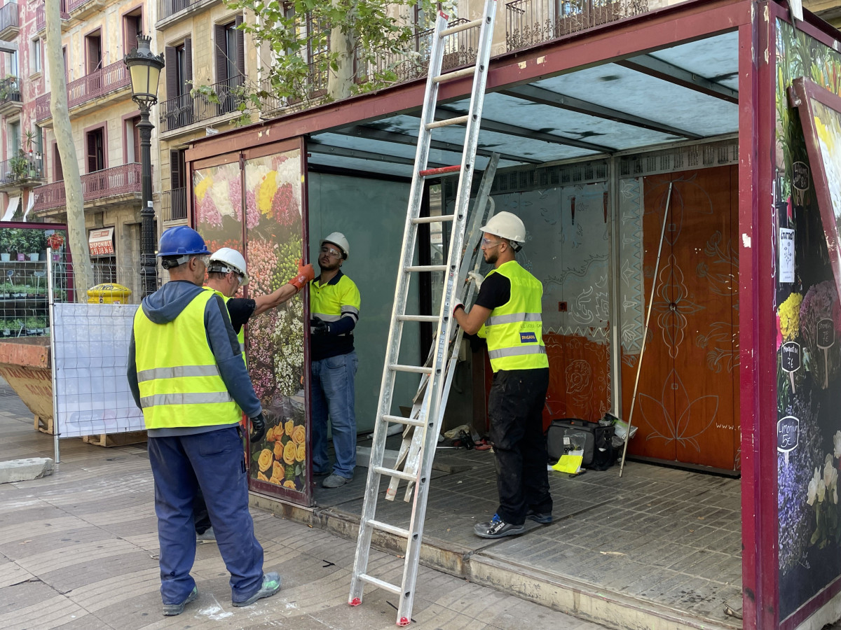 Operarios desmontan una parada de flores de la Rambla este martes.