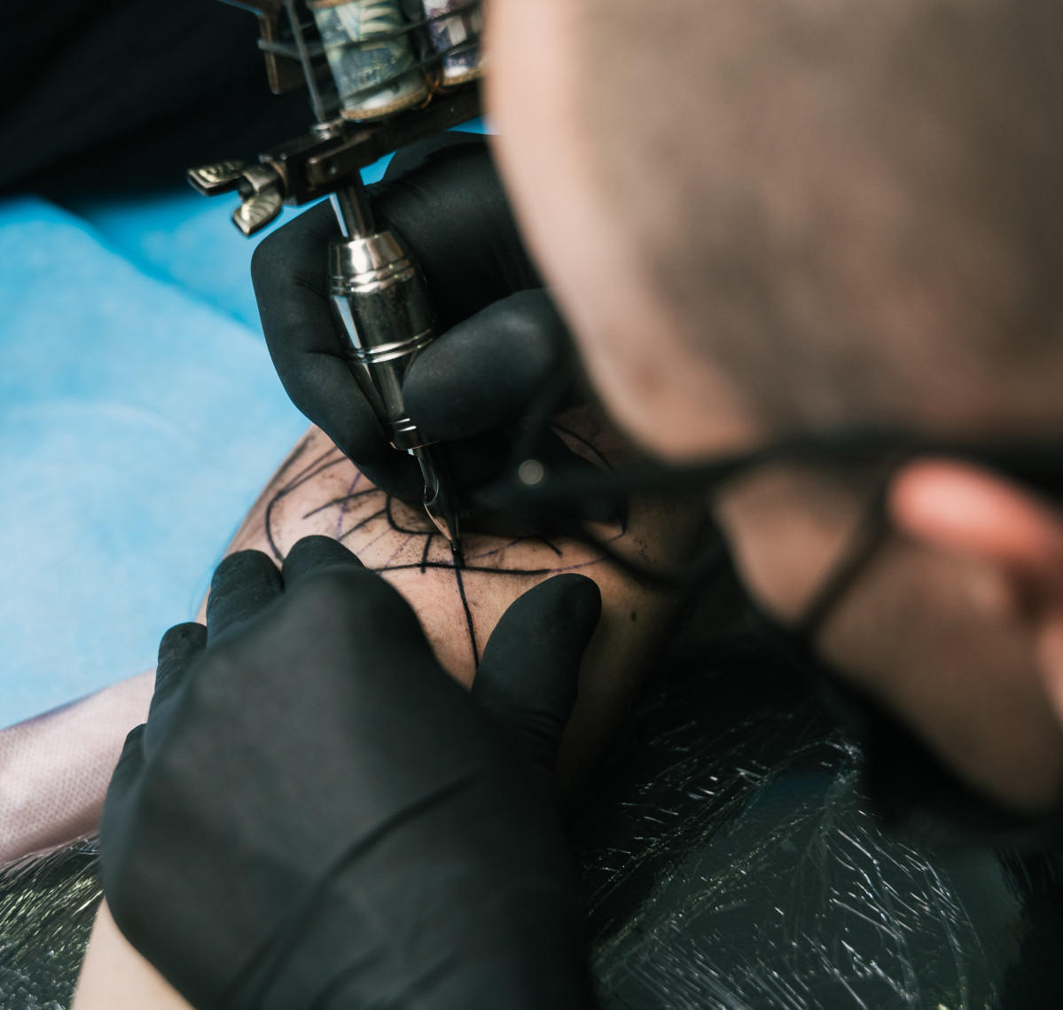 Selective focus shot tattoo artist with black gloves creating tattoo man s arm