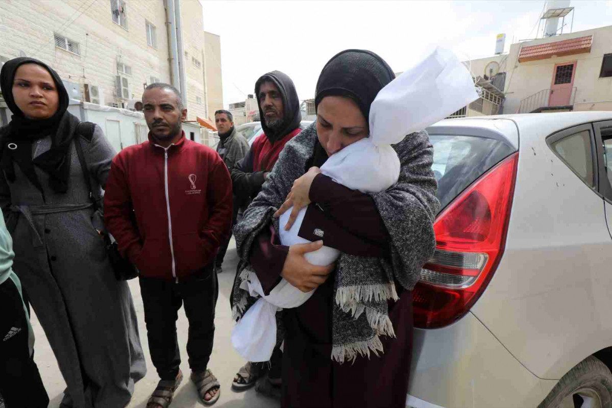 Familiares del bebé palestino Bassam El Maquse, que murió en ataques israelíes, lloran mientras reciben su cuerpo de la morgue del Hospital Al Aqsa para su entierro en Dair El Balah, Gaza, el 22 d