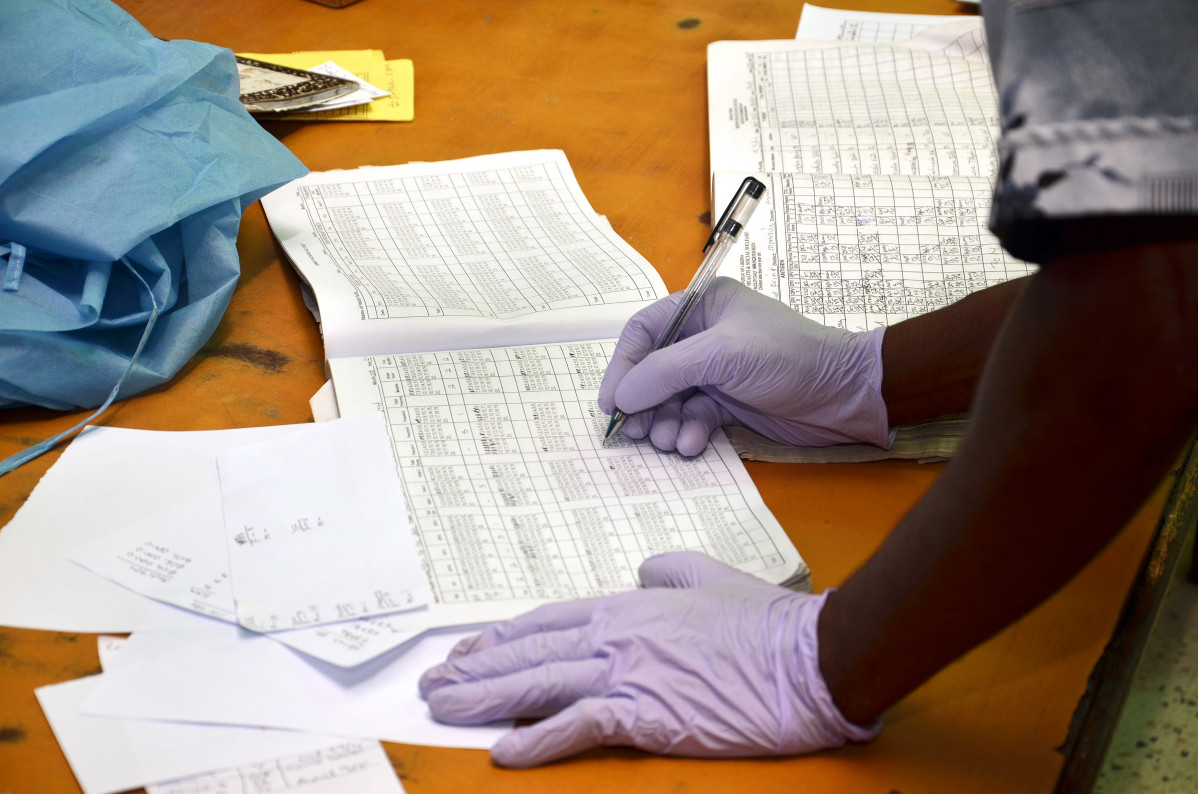 Una persona con guantes de látex rellena unos datos en un cuaderno